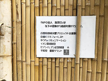 加茂女　竹の倉庫に表示されている、夏原グラントのロゴマーク、他の支援団体の名前もある