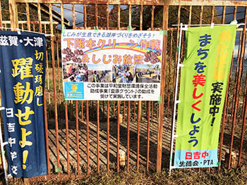 下阪本子どもコミュニティー　活動のようす　日吉中学ののぼりの真ん中に、「下阪本クリーン作戦＆しじみ放流」という幕。夏原グラントのロゴマークも入れてもらっています
