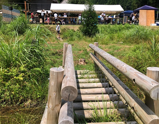 Woodstick　桂川を守る会　里山交流イベントの日、ビオトープにかかる木製の橋から、音楽ライブをしているウッドデッキを望む