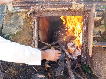 東草野炭焼き文化保存会　焚口から火をくべる