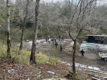 一般社団法人　甲賀ナイスローカルカンパニー　活動のようす画像　　里山の斜面に囲まれた広場に皆さんが集まって作業しているところ